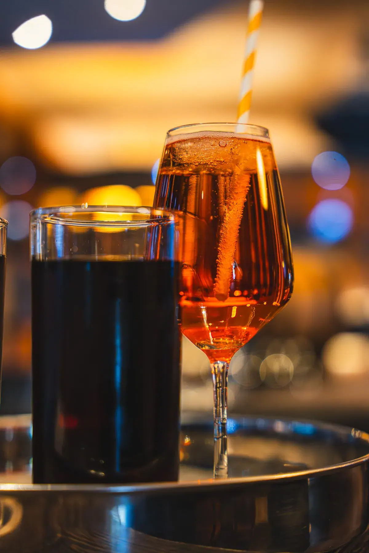Spritz und Cola auf dem Tablett, warmes Licht im Gastraum