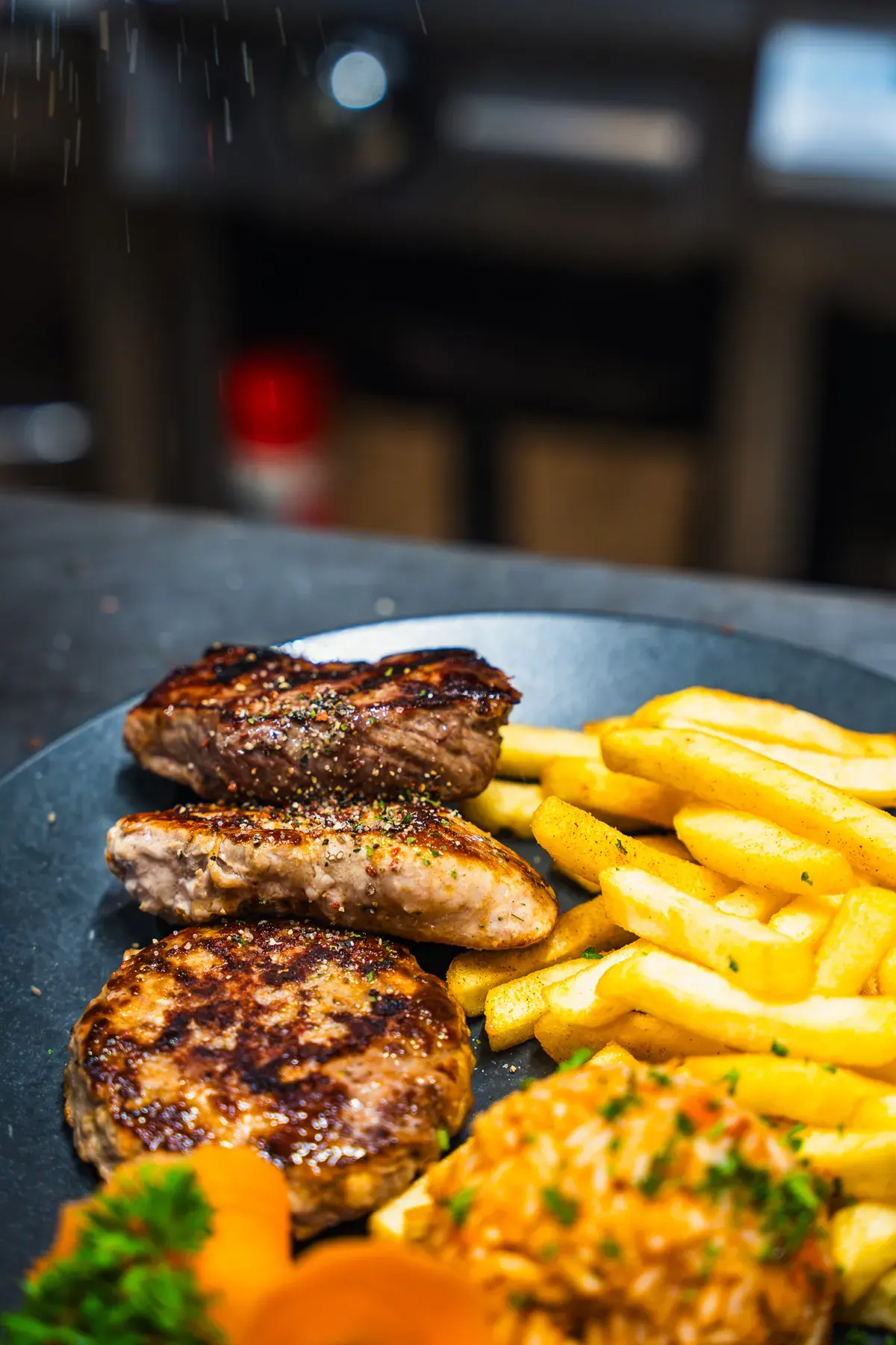 Steaks vom Grill mit Pommes frites auf dunklem Teller