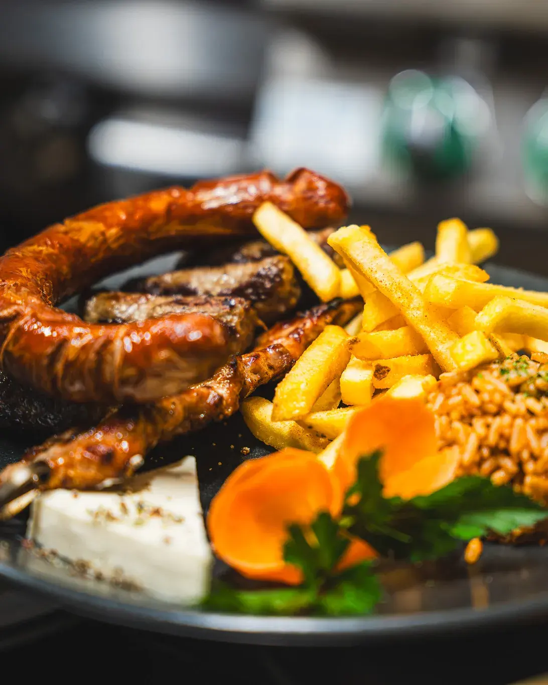 Räuberteller mit Grillwurst, Fleischspieß, Pommes frites, Djuwetschreis und Hirtenkäse