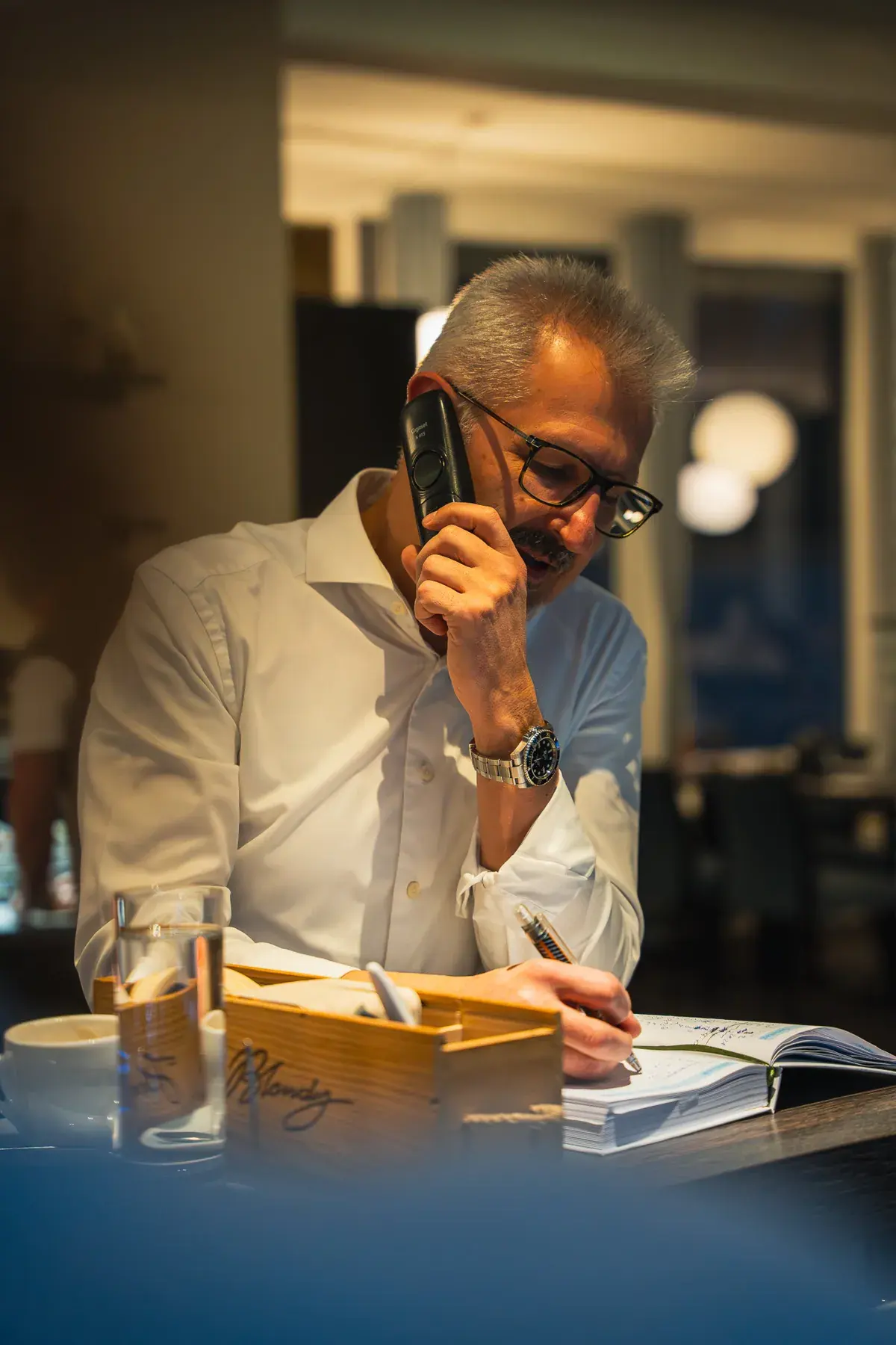 Slaven am Telefon, vor ihm das Reservierungsbuch